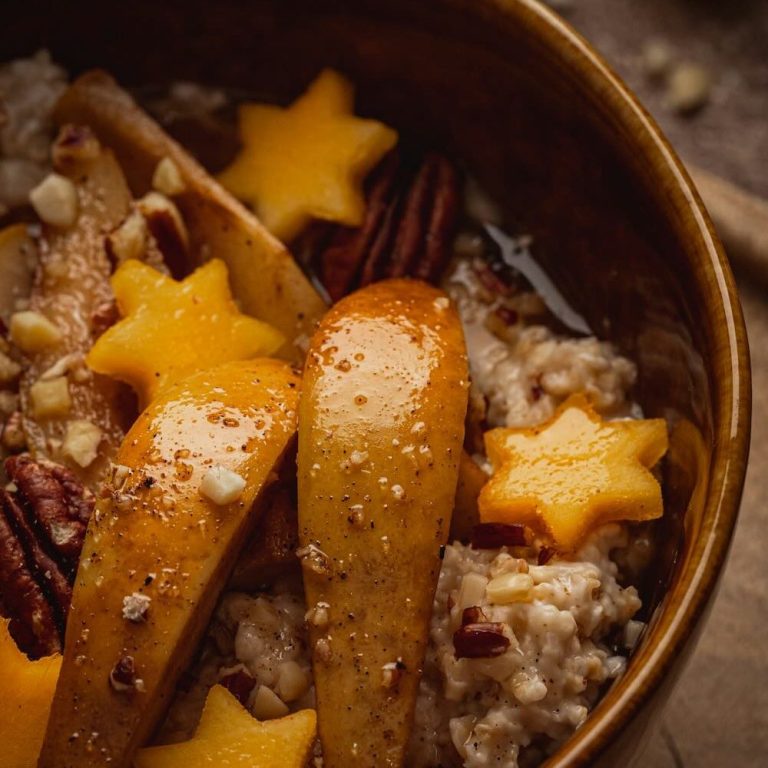 Warmer Porridge in einer Tonschüssel mit herbstlichen Obst-Sternen und Nüssen – gesundes Frühstück für die Ayurveda Vata-Zeit.