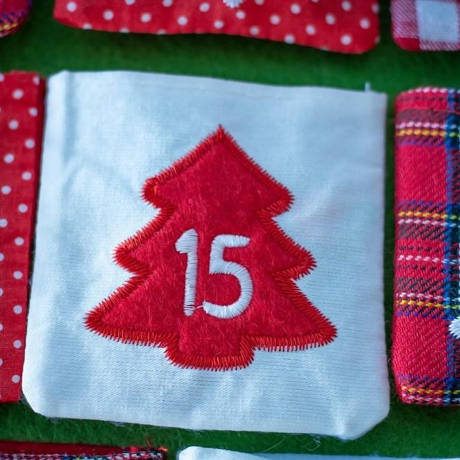 Adventskalenders mit weißen Türchen und rotem Tannenbaum-Motiv und der Zahl 15 – Hinweis auf den Pinterest-Adventskalender.
